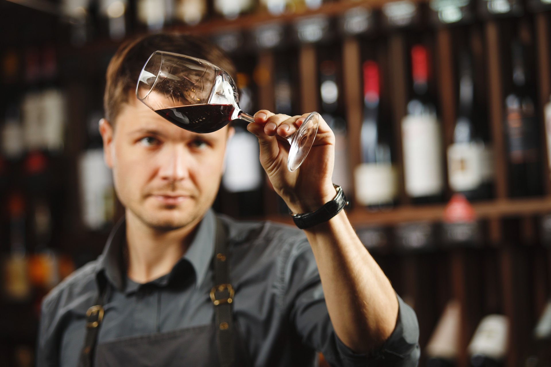 Bokal of red wine on background, male sommelier appreciating drink