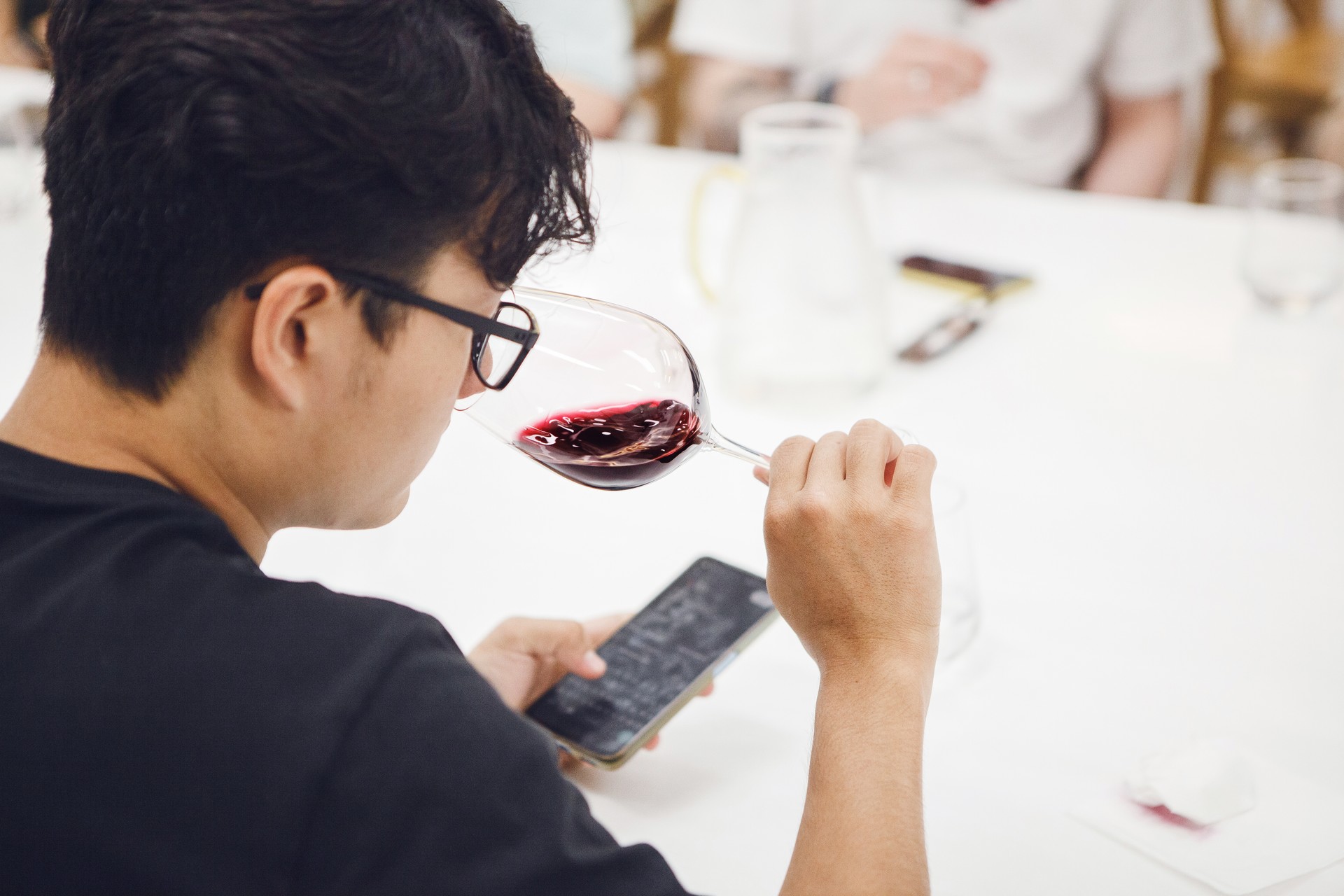 Asian ethnicity sommelier wearing in black t-shirt tasting white wine during wine experts lecture or training. Wine experts association, sommelier school, professional development.